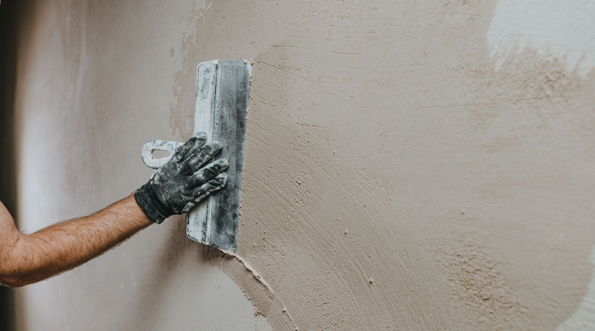 Builder in work overalls plastering a wall indoor